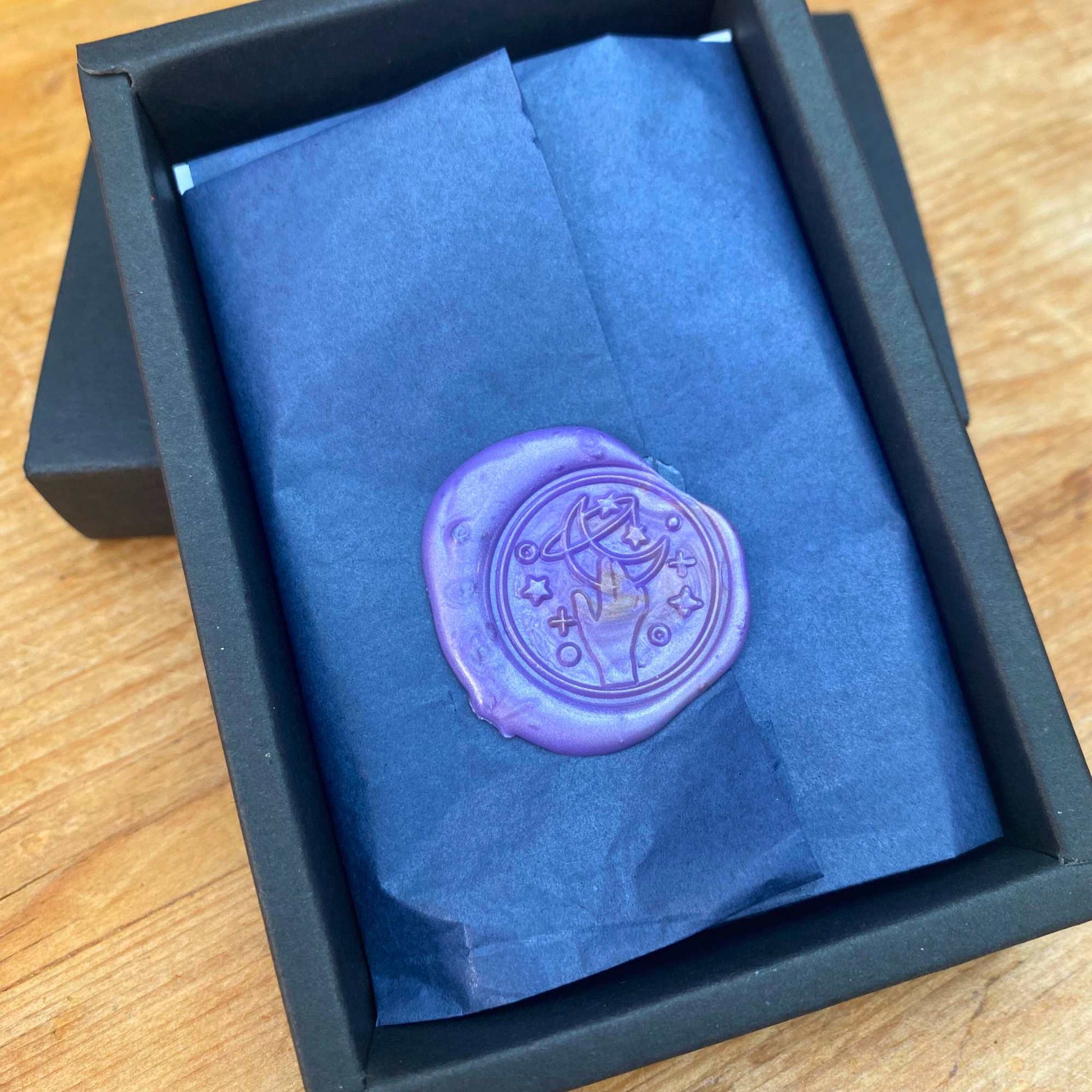 Example of the black recycled card sliding packaging box with deep blue tissue and handmade wax stamp with celestial pattern