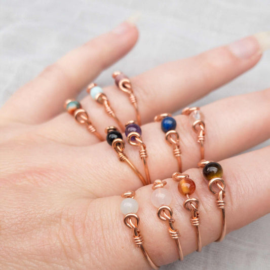 hand showing collection of single crystal fidget rings made in copper wire