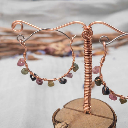 watermelon tourmaline wire wrapped handmade hoop earrings hanging on copper wire stand
